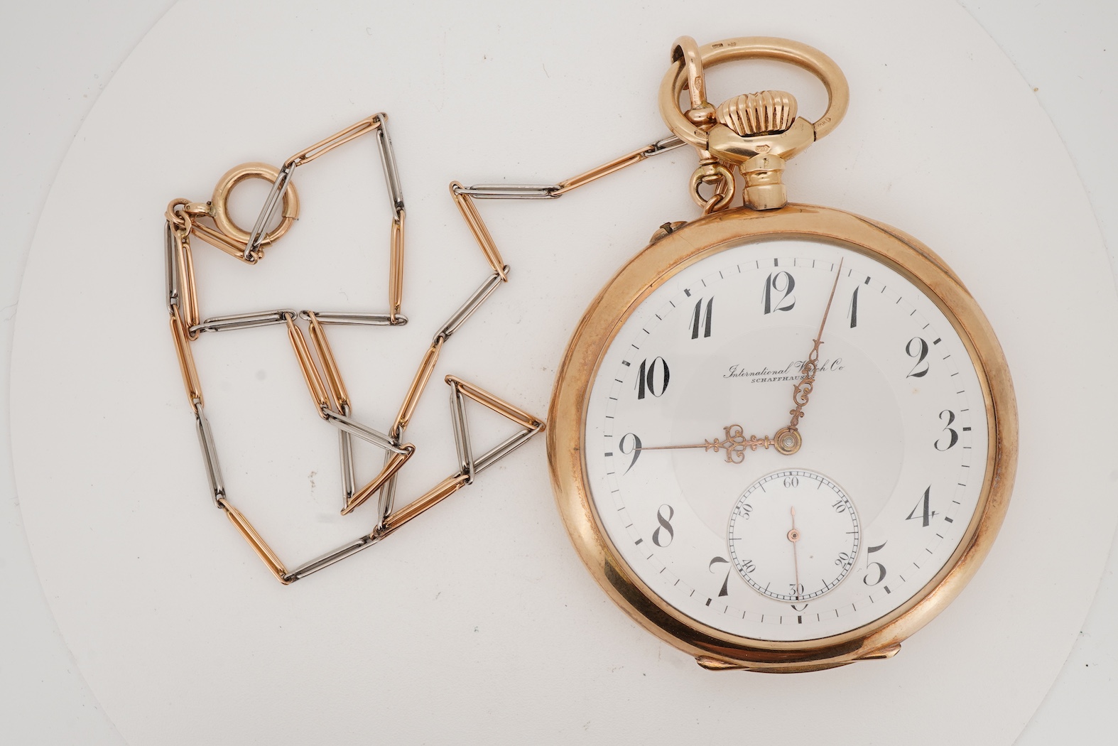 An early 20th century International Watch Company engine turned 14k yellow metal open faced keyless lever pocket watch, together with a Viennese? two colour yellow metal albert, maker's mark, LE